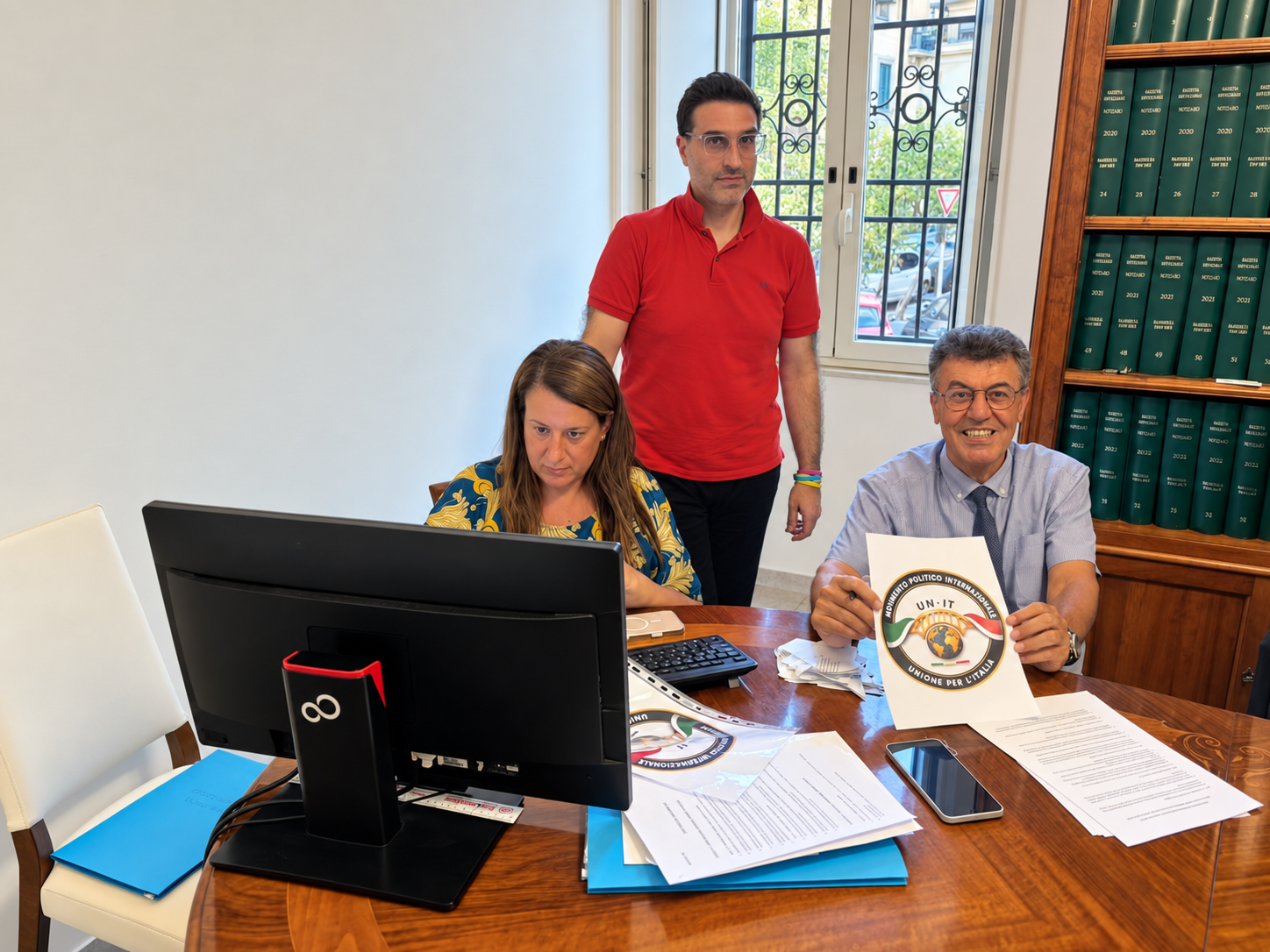 Tre partecipanti alla riunione con il logo UN.IT mostrato su un documento